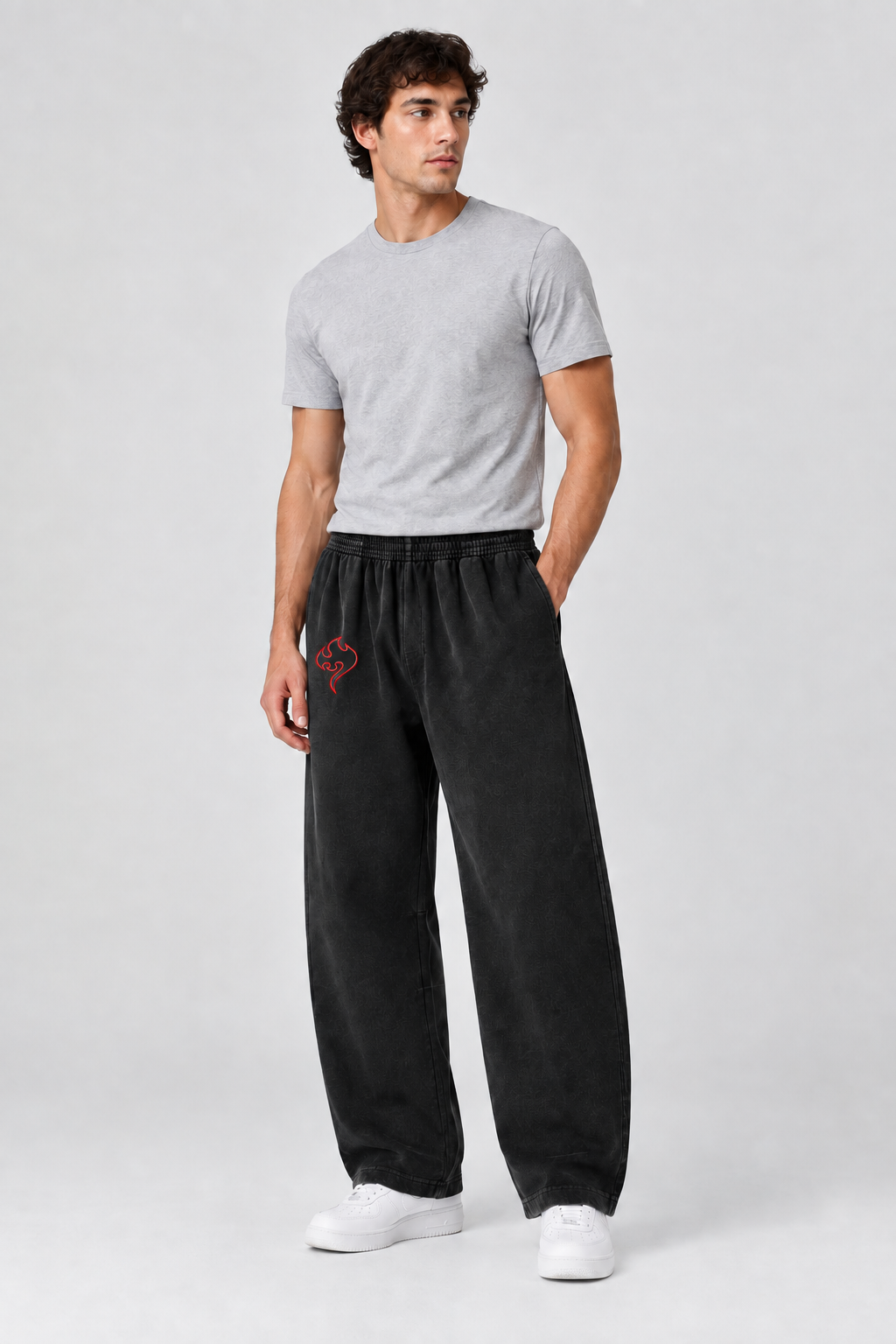 Model wearing black vintage-washed barrel-leg sweatpants with red thigh emblem