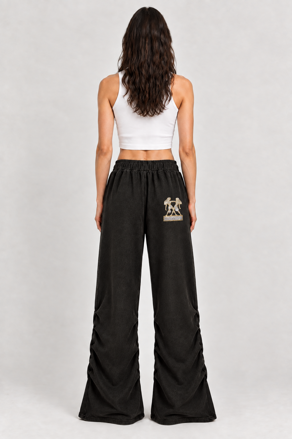 Female model wearing black Gemini vintage wash ruched sweatpants, back view; zodiac graphic is illustrative