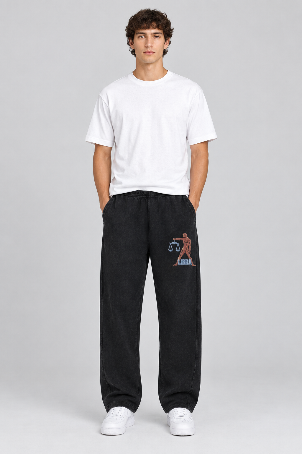 Male model wearing black Libra mineral wash straight sweatpants with figure and scales on front thigh; illustrative print