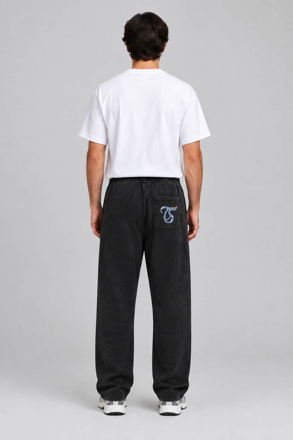 Male model wearing black Aquarius mineral wash straight sweatpants, back TS pocket mark; illustrative print