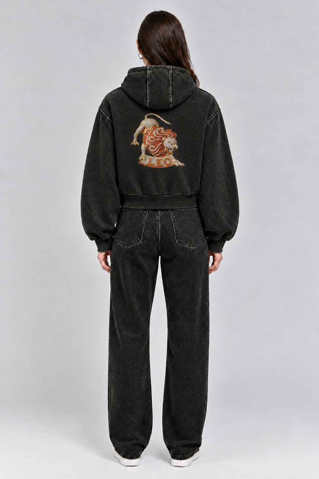 Female model wearing black Leo vintage wash full zip hoodie, back view; print is illustrative