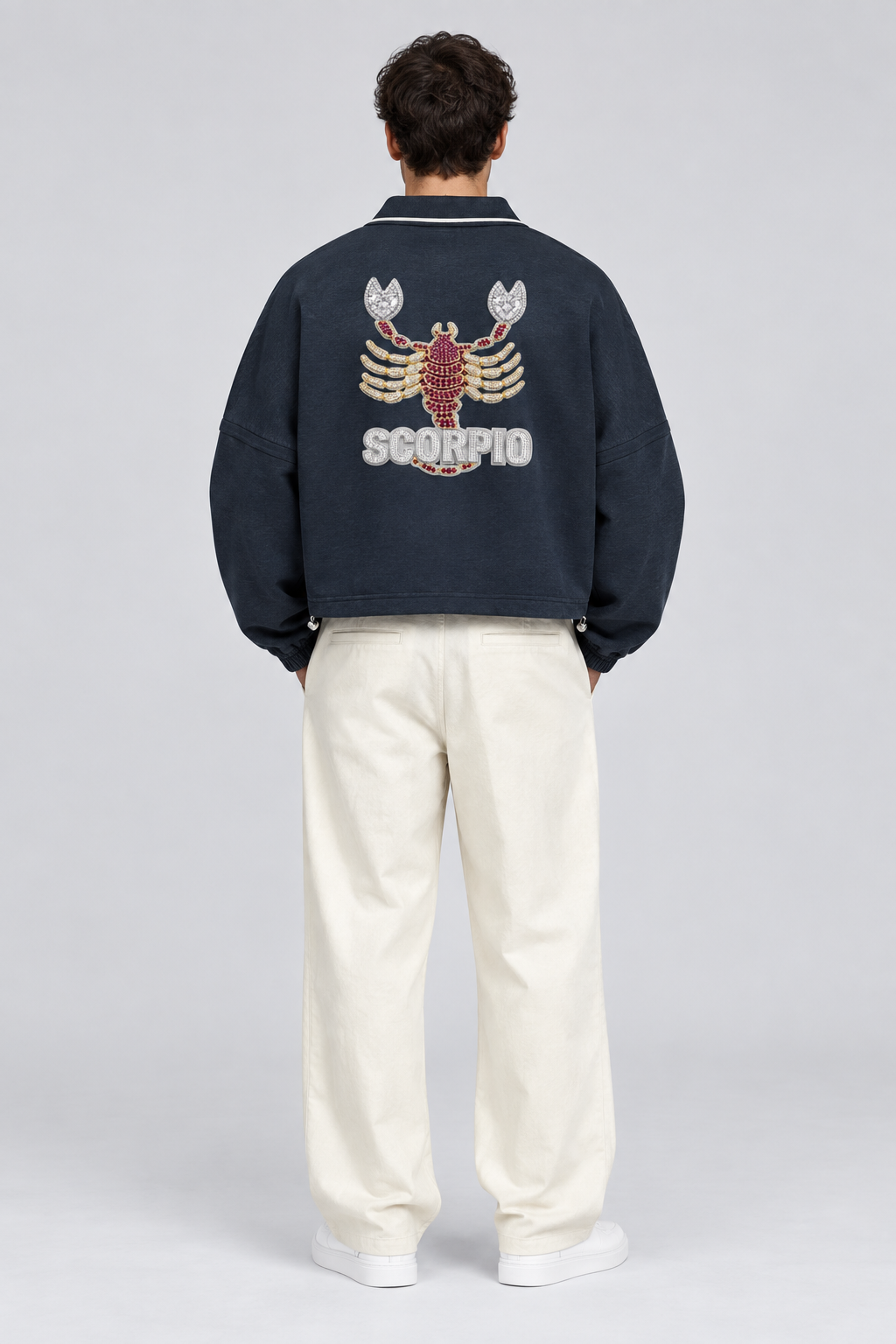 Male model wearing Scorpio unisex boxy collared detachable sweatshirt with scorpion artwork, back view; illustrative styling image