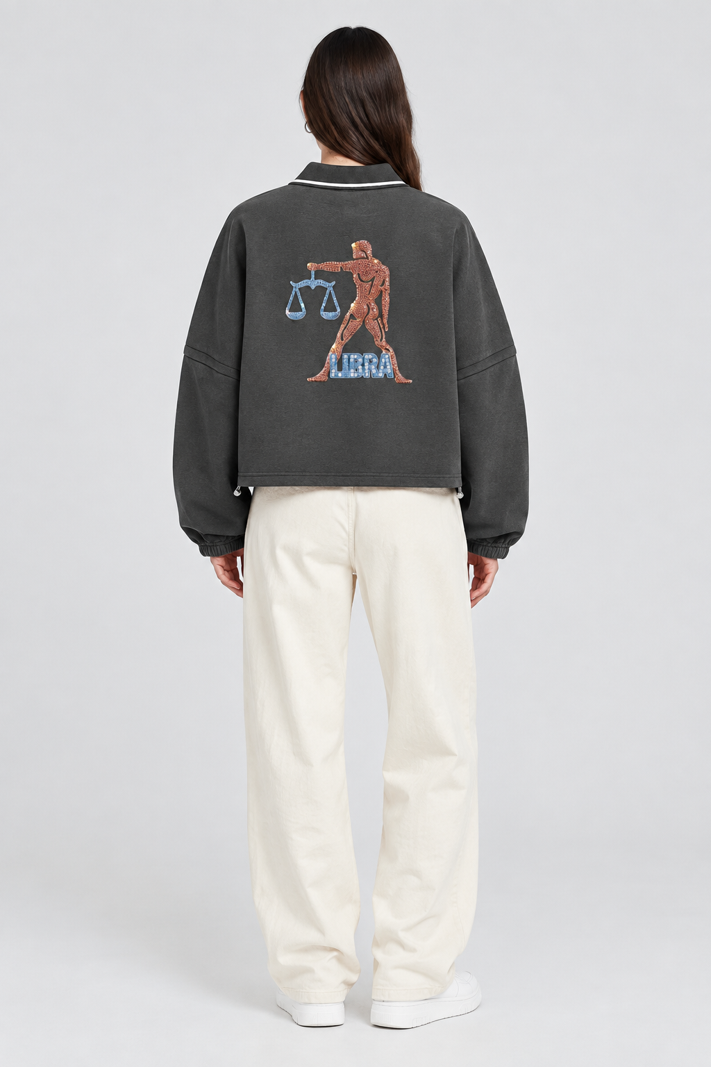 Female model wearing Libra unisex boxy collared detachable sweatshirt with scales artwork, back view; illustrative styling image