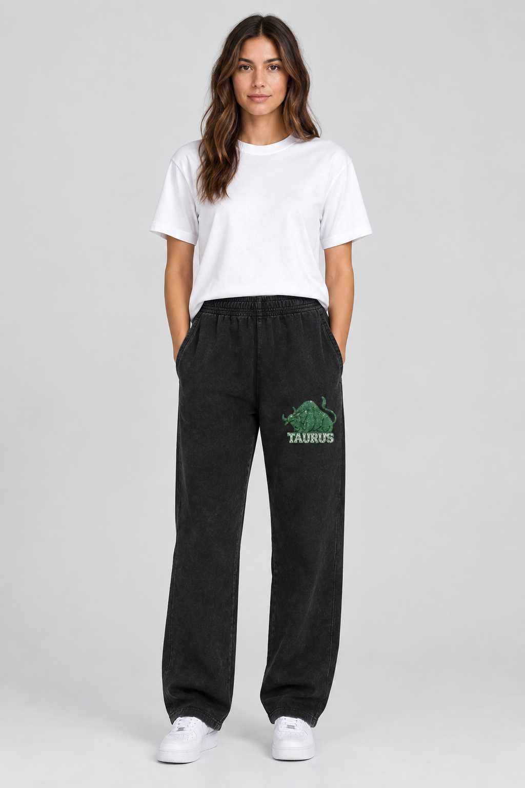 Female model wearing black Taurus mineral wash straight sweatpants with Taurus front-thigh art; print is illustrative