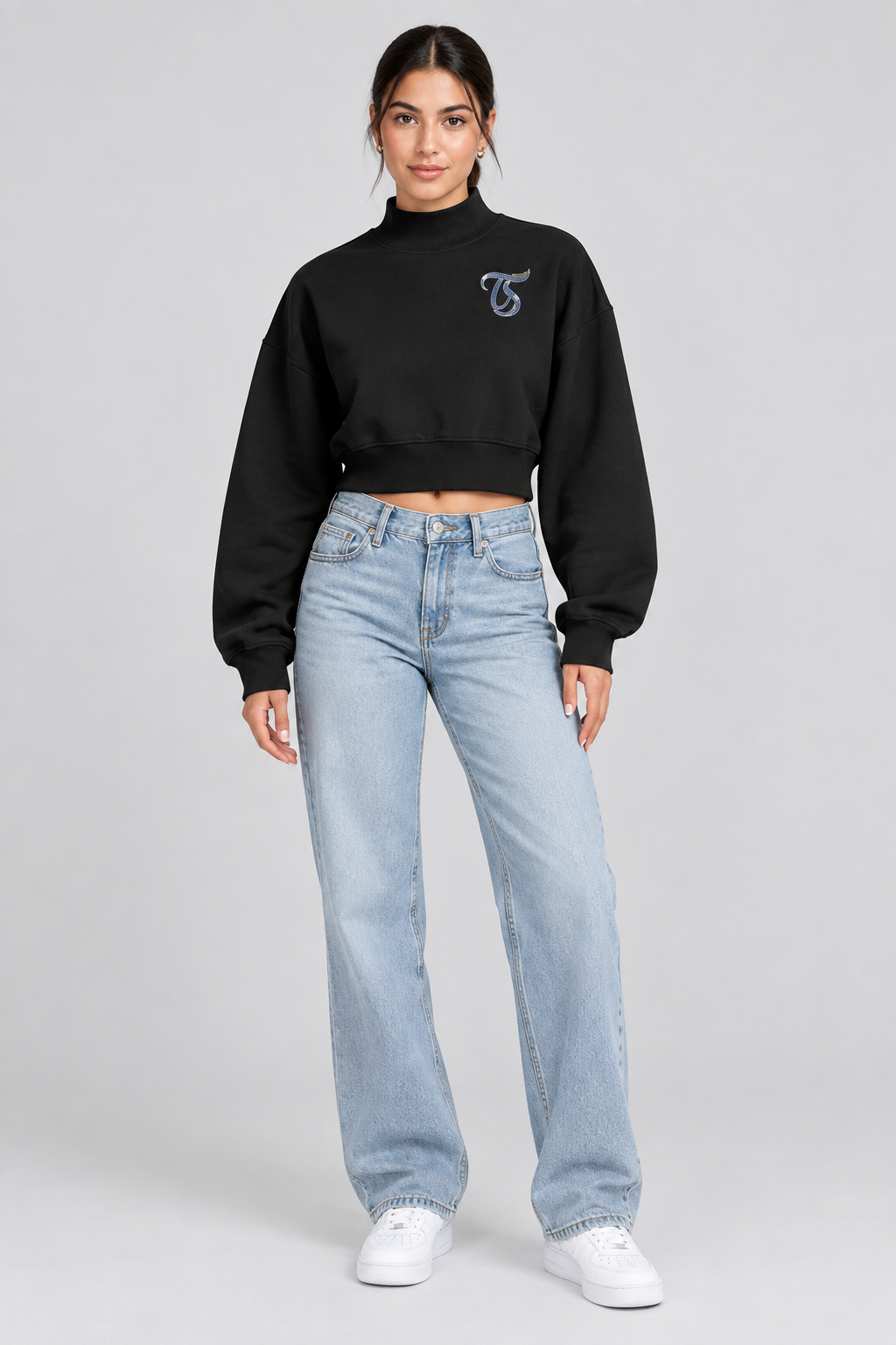 Female model in black Gemini women's crop mock neck sweatshirt, front with TS logo; illustrative print
