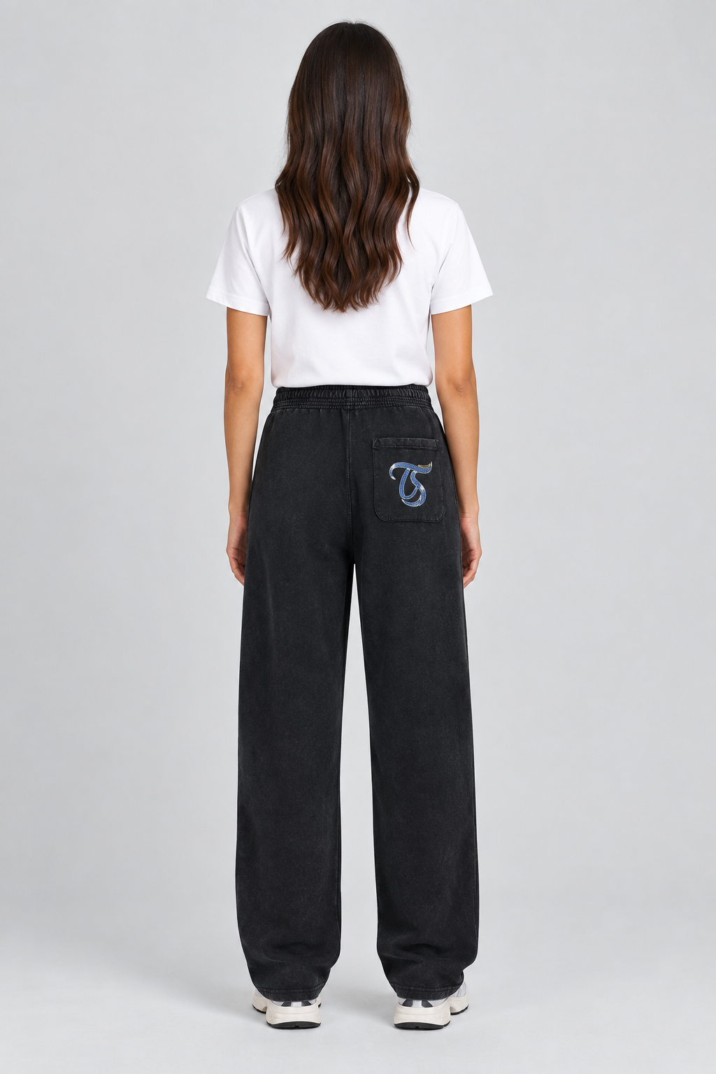 Female model wearing black Taurus mineral wash straight sweatpants with TS back-pocket mark; print is illustrative