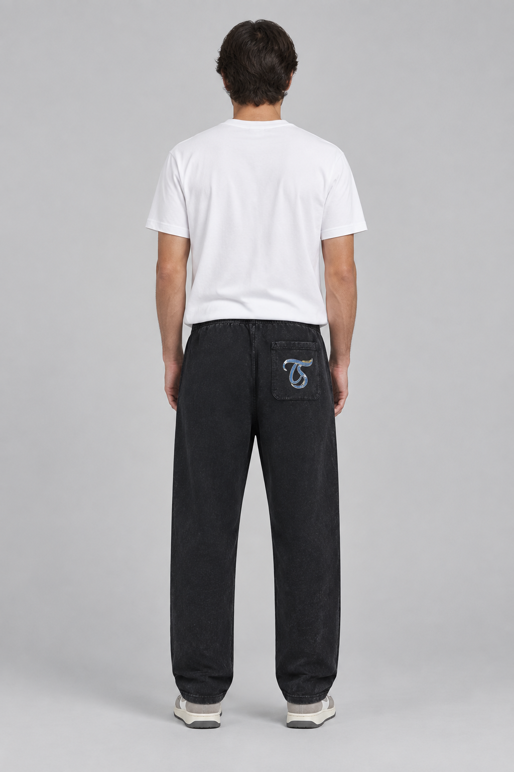 Male model wearing black Aries mineral wash straight sweatpants with TS back-pocket logo; print is illustrative