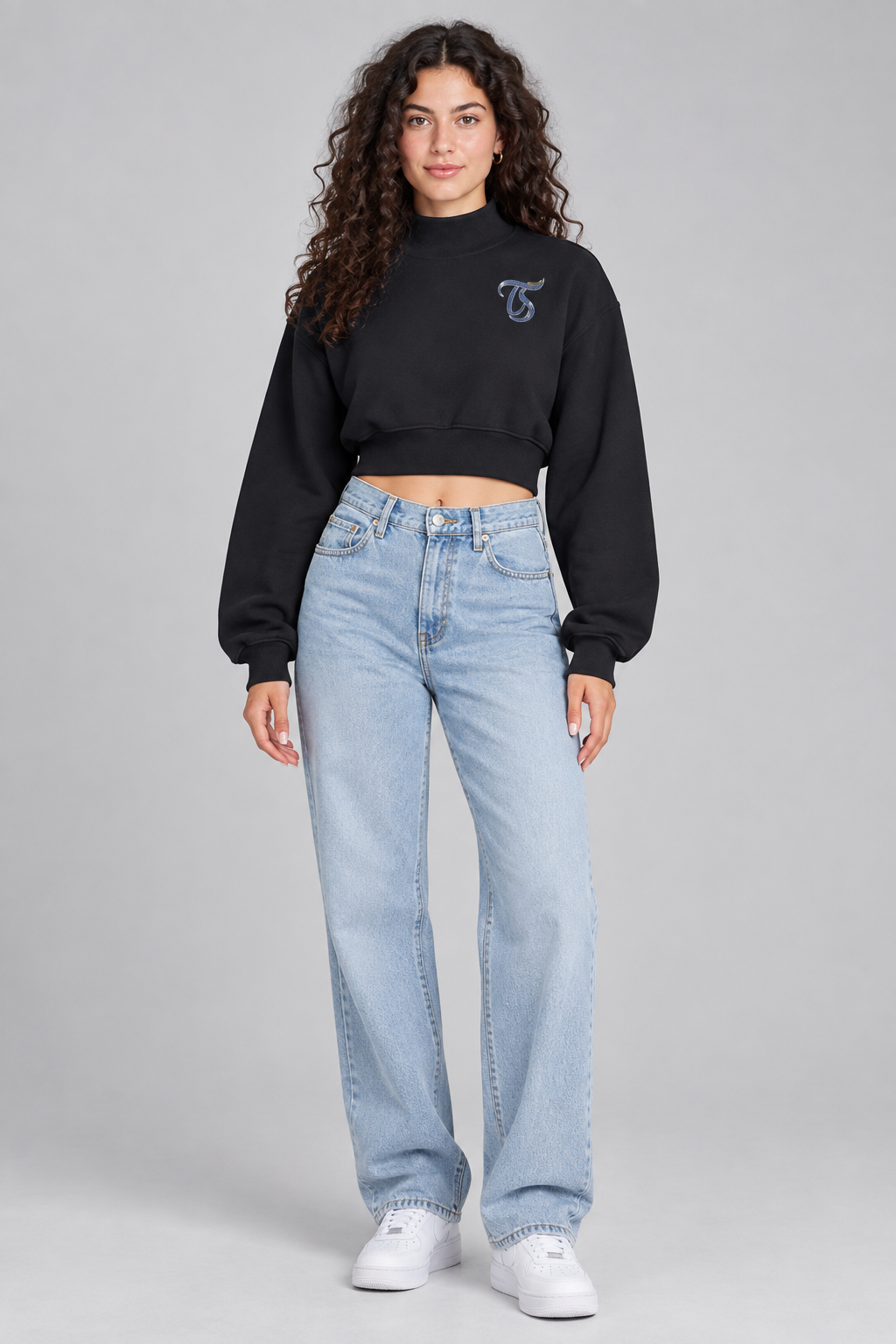 Female model in black Leo women's crop mock neck sweatshirt, front with TS chest mark; illustrative print