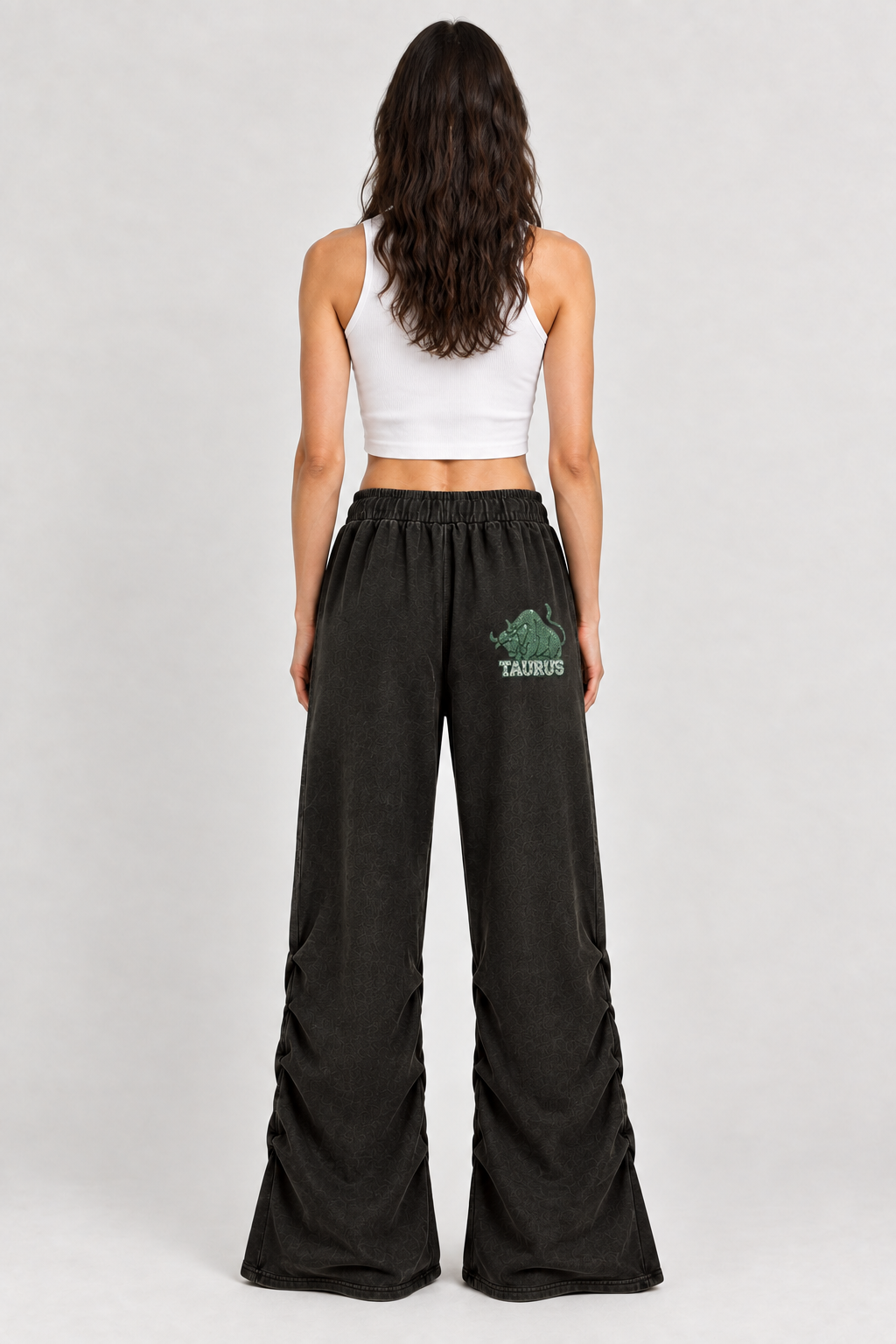 Female model wearing black Taurus vintage wash ruched sweatpants, back view; graphic is illustrative