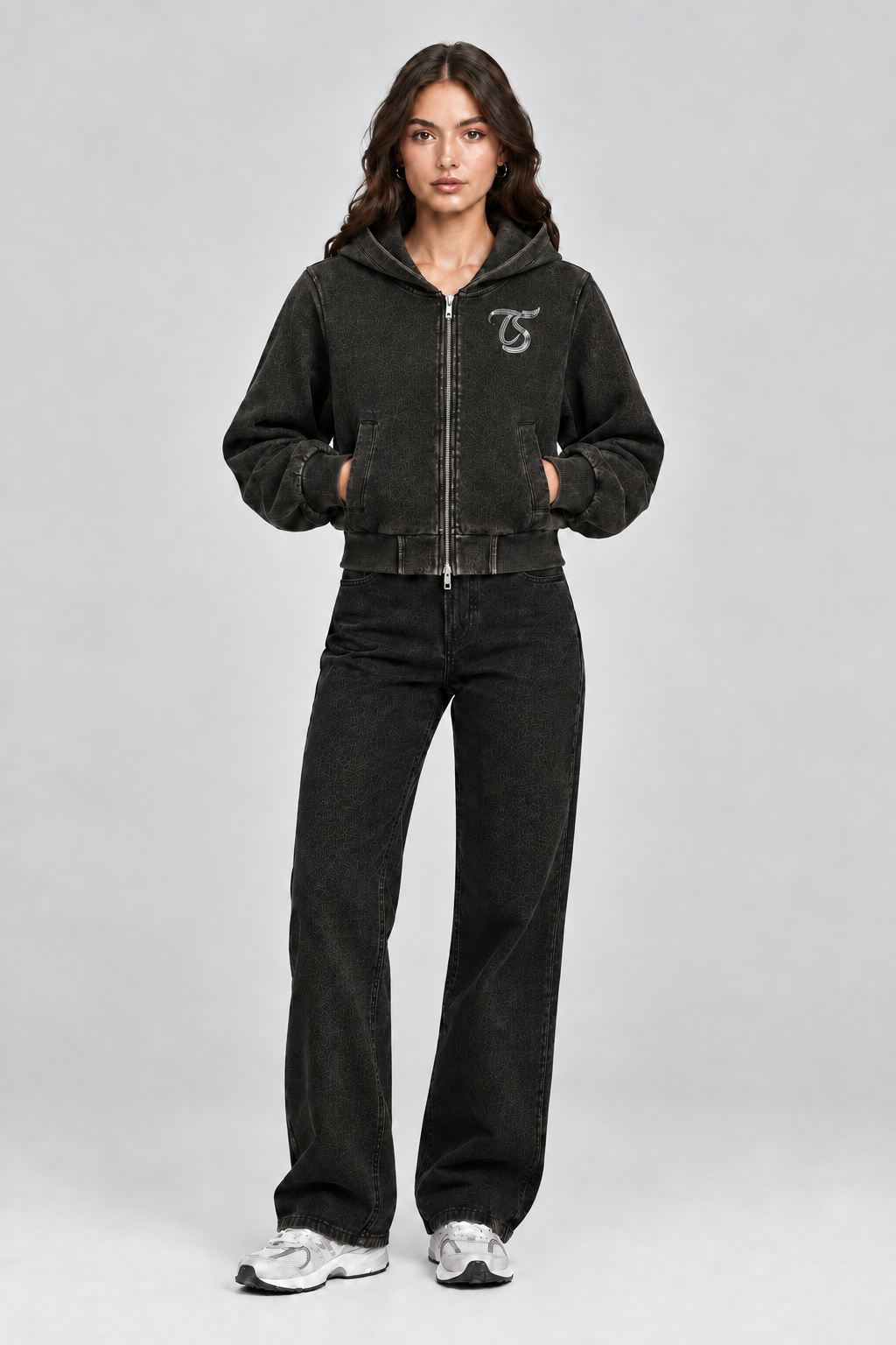 Female model wearing black Gemini vintage wash full zip hoodie with TS logo, front view; print is illustrative
