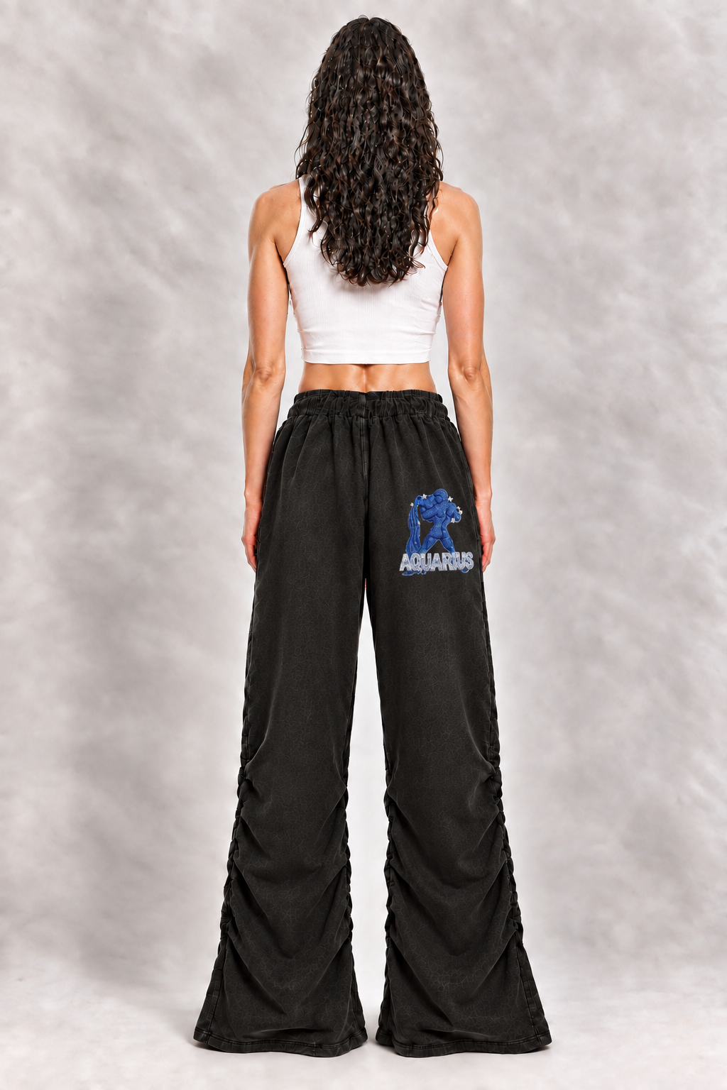 Female model wearing black Aquarius vintage wash ruched sweatpants, back view; zodiac graphic is illustrative
