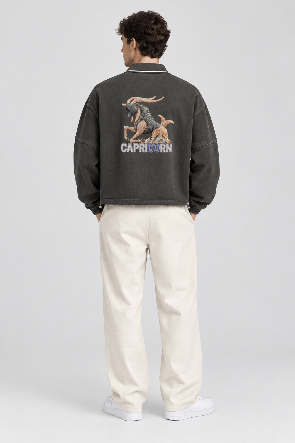 Male model wearing Capricorn unisex boxy collared detachable sweatshirt with goat artwork, back view; illustrative styling image