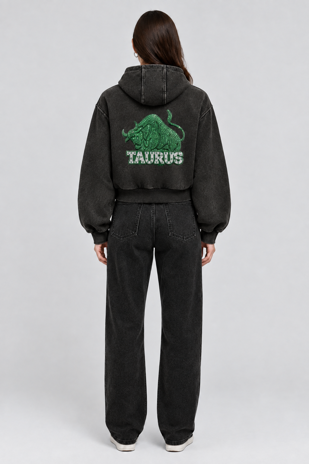 Female model wearing black Taurus vintage wash full zip hoodie, back view; print is illustrative