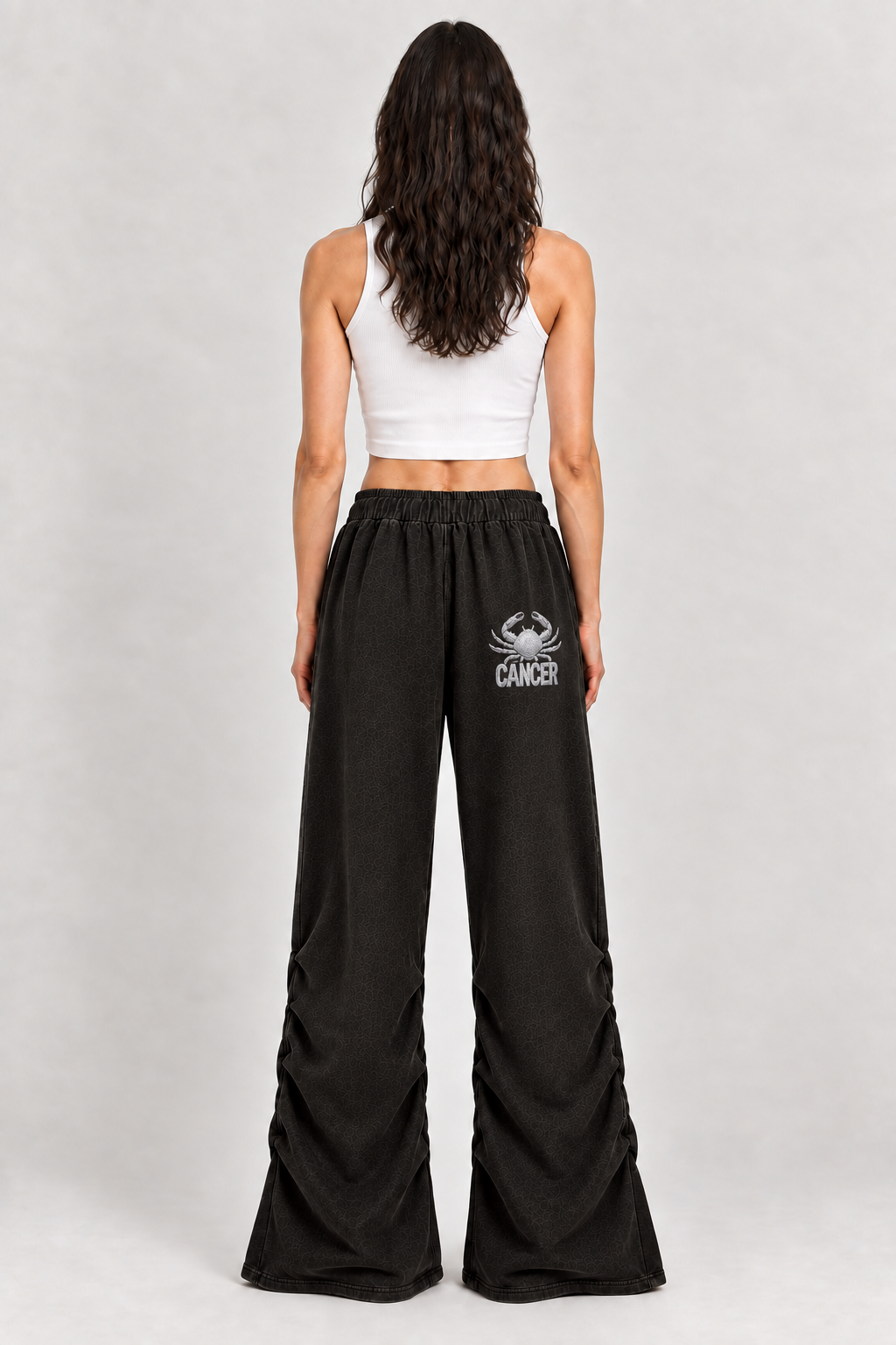 Female model wearing black Cancer vintage wash ruched sweatpants, back view; zodiac graphic is illustrative