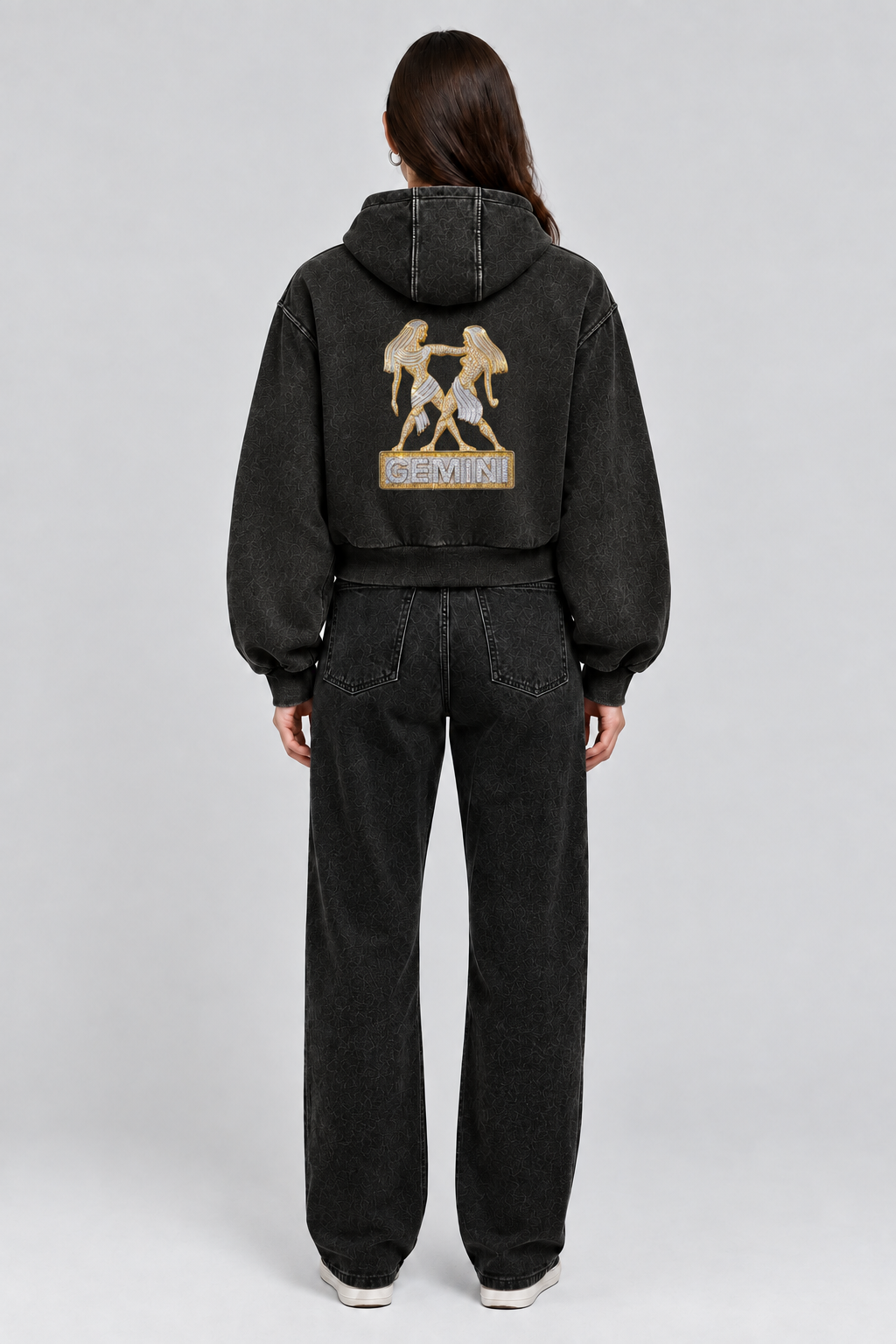 Female model wearing black Gemini vintage wash full zip hoodie, back view; print is illustrative