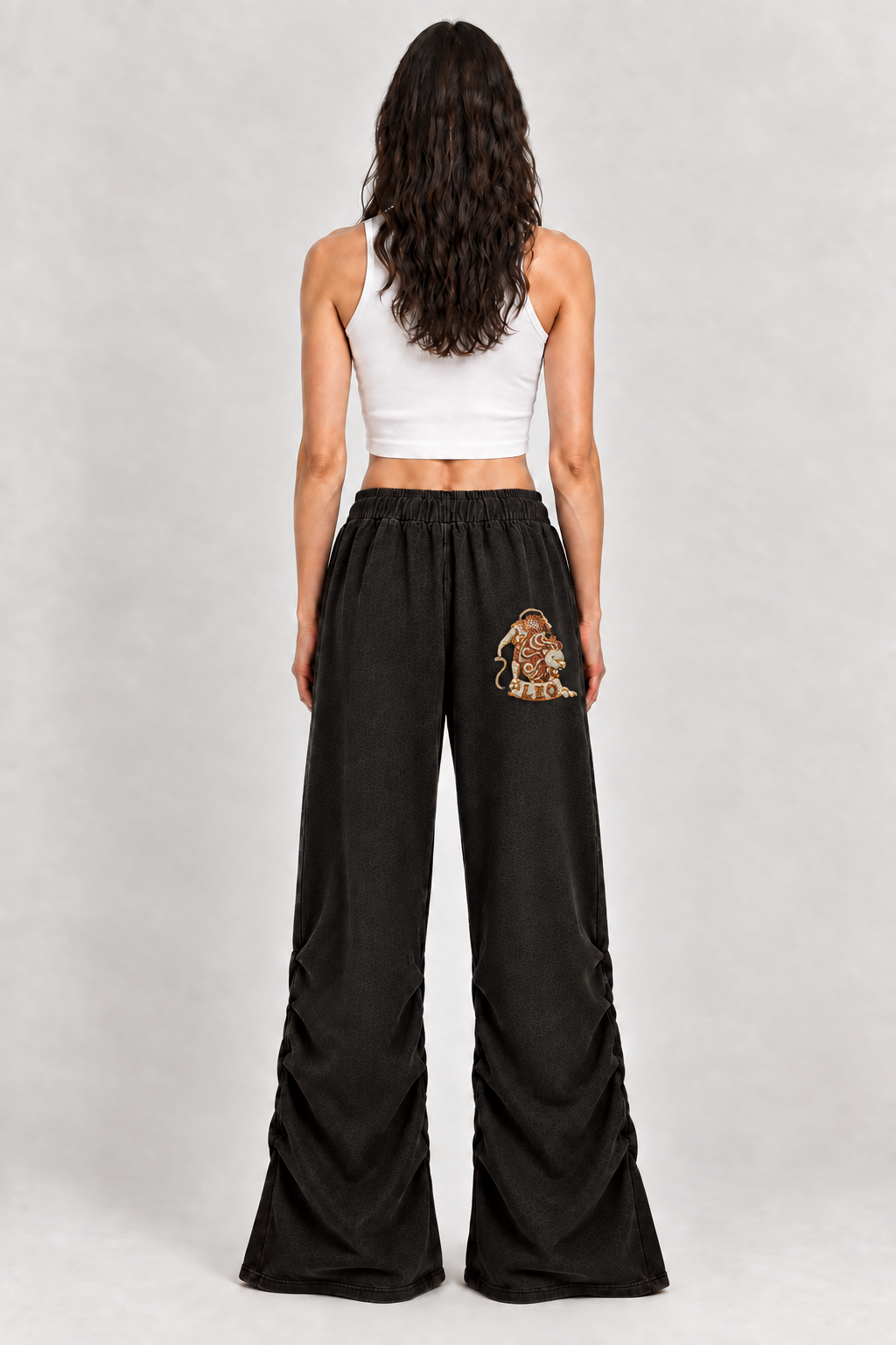 Female model wearing black Leo vintage wash ruched sweatpants, back view; zodiac graphic is illustrative