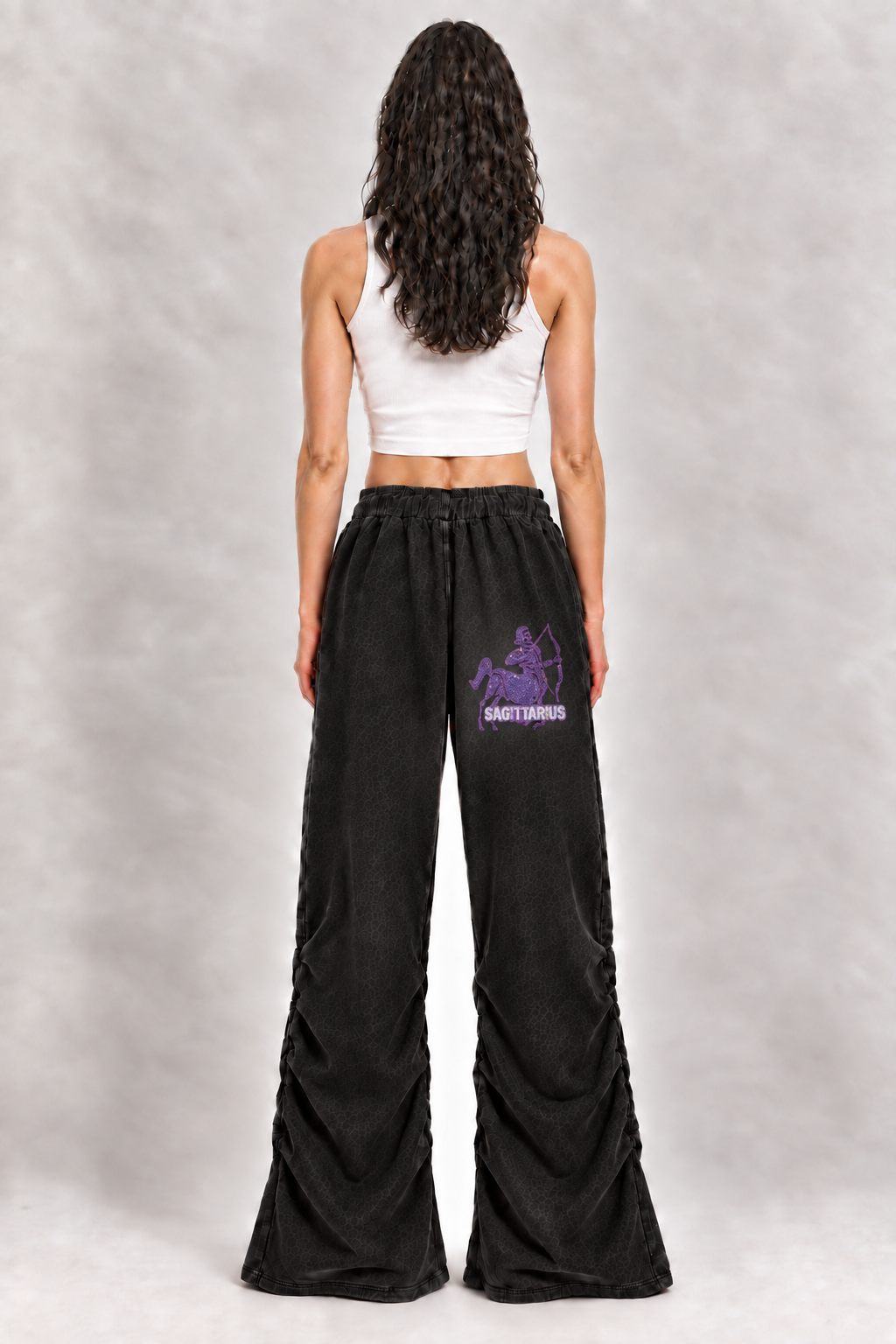 Female model wearing black Sagittarius vintage wash ruched sweatpants, back view; zodiac graphic is illustrative