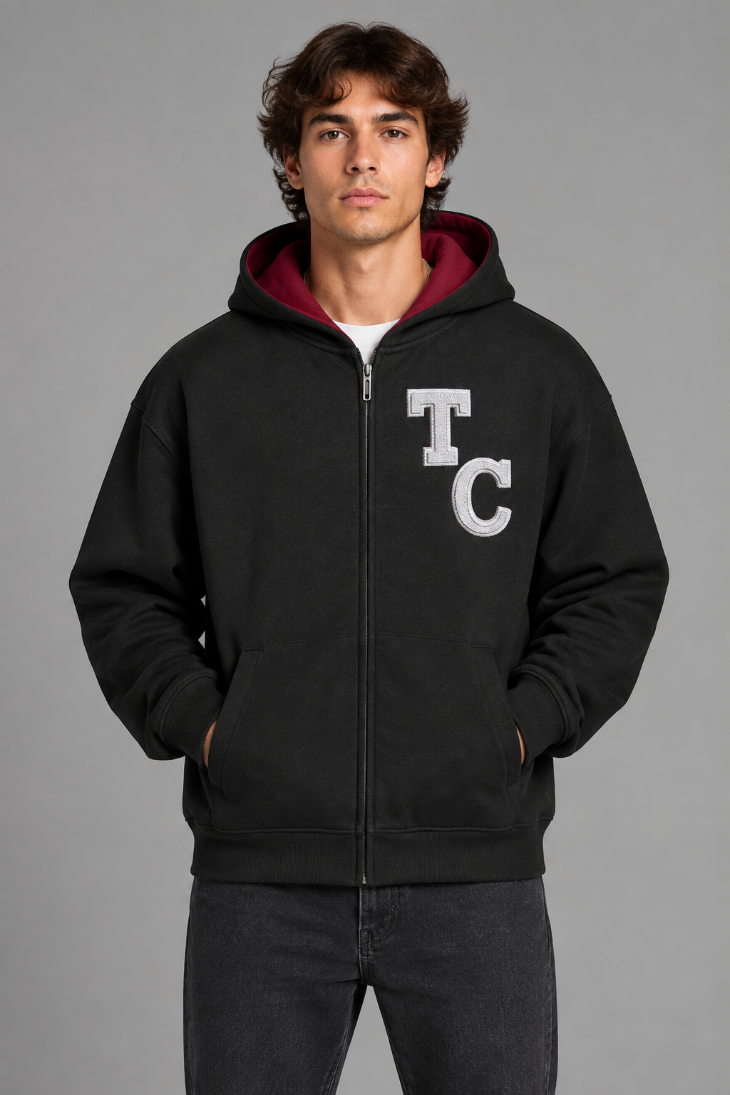 Model wearing black The Crew drop shoulder full zip hoodie, front view; artwork is illustrative