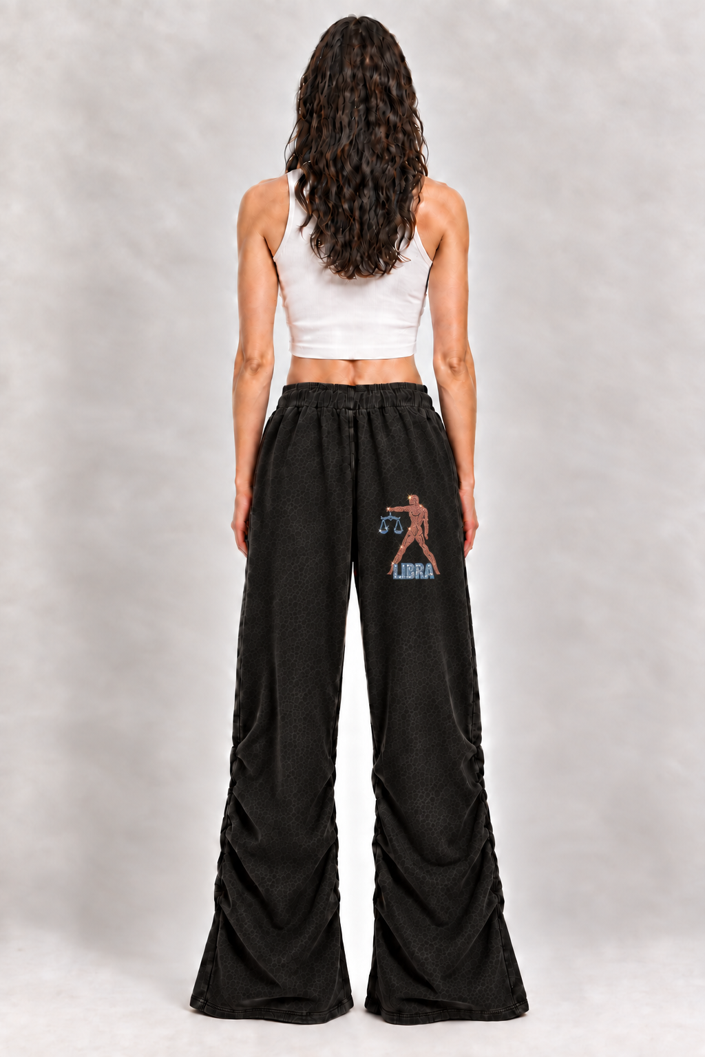 Female model wearing black Libra vintage wash ruched sweatpants, back view with small Libra figure, scales and LIBRA lettering; artwork is illustrative