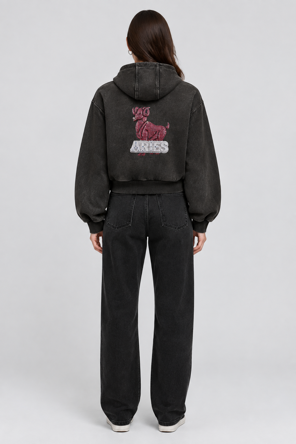 Female model wearing black Aries vintage wash full zip hoodie, back view; print is illustrative